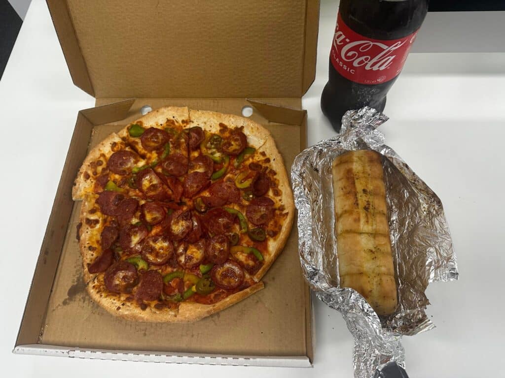 Top view of Mexicana pizza, garlic bread, and coke cola