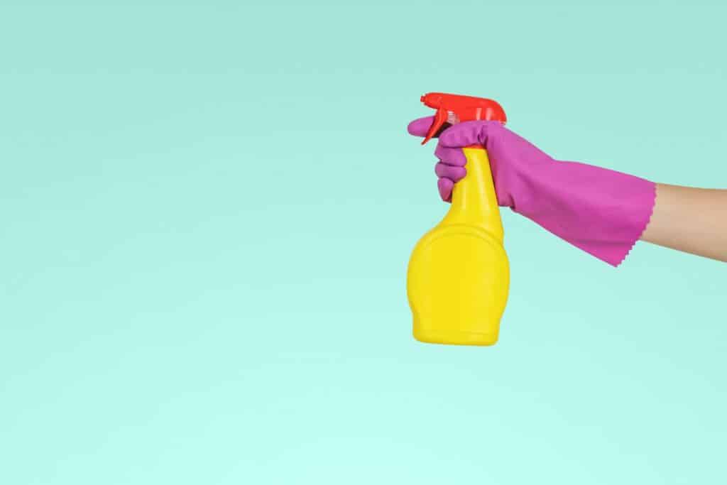 hand holding yellow plastic spray bottle cleaner