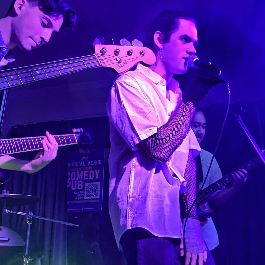 A band perform under purple pink light in The Rubber Chicken pub